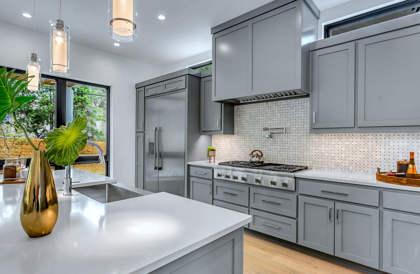 Grey fitted kitchen with white worktops and mosaic splashback tiles